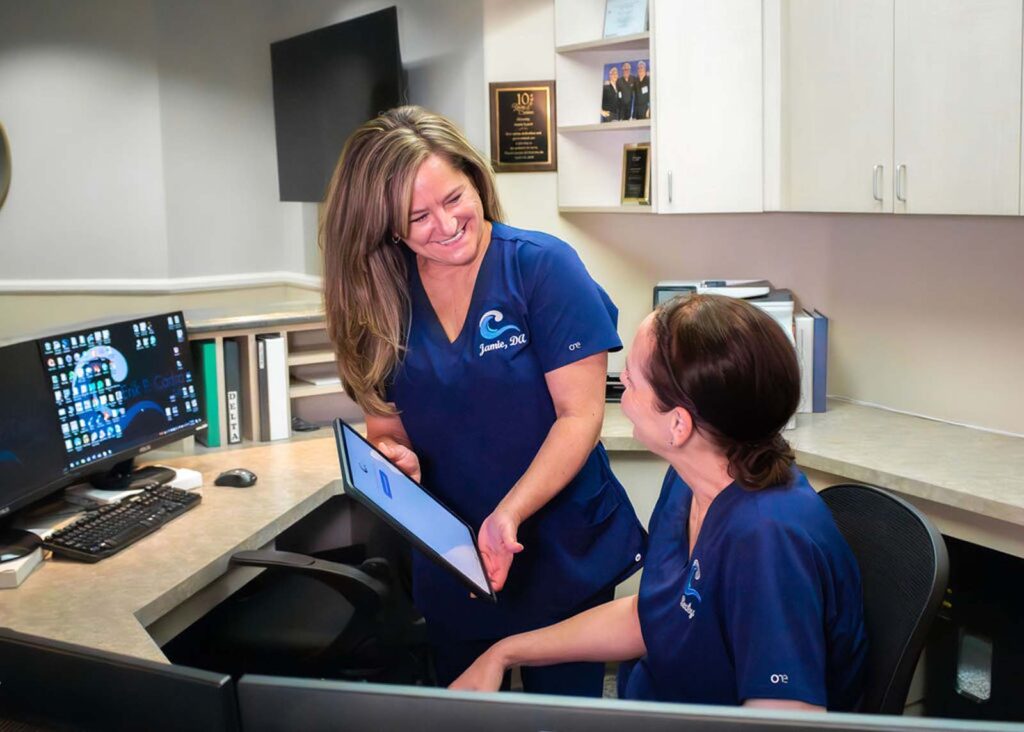 Photo of team members talking behind the front desk at Erik P. Cadra, DMD.