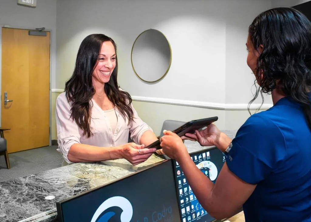 Helping a patient at the front desk of Erik P. Cadra, DMD.
